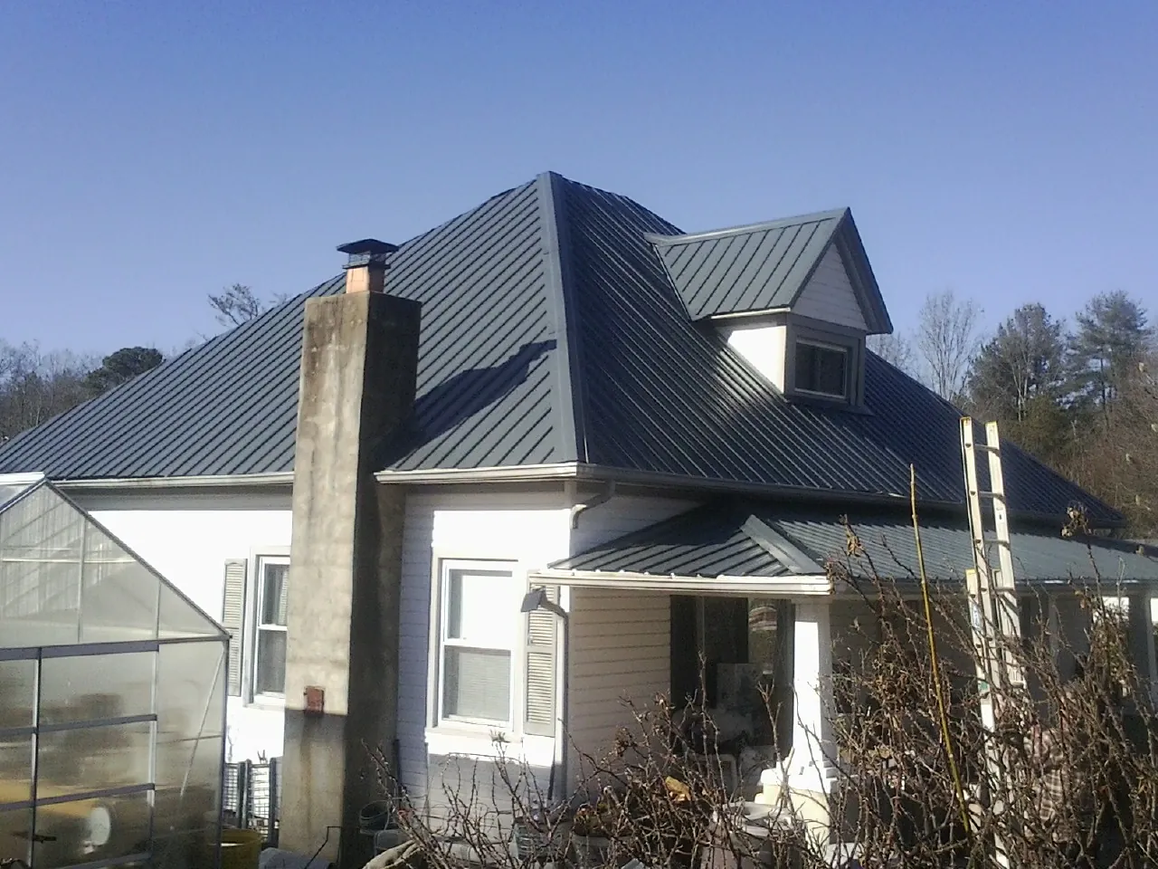 Dark blue standing seam metal roof on a white farmhouse with dormer — Slate & Tile Roof Repair by Roofing Brothers in Denver