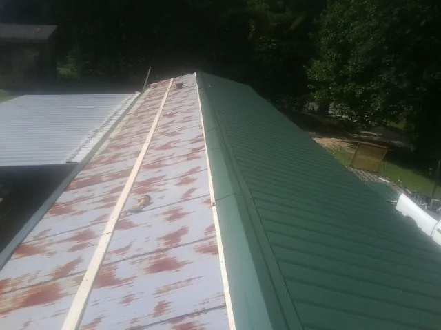 Old rusted panels beside newly installed green metal roofing — Wind Damage Roof Repair by Roofing Brothers in Denver
