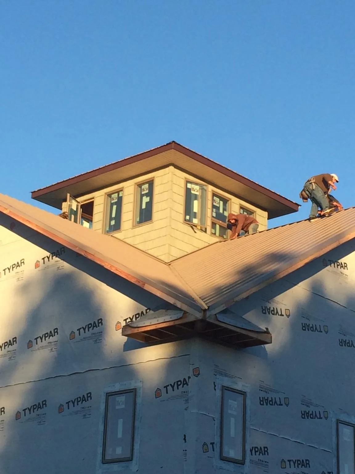 Roofers working around a rooftop cupola on a new metal roof at sunset — Roof Waterproofing in Denver by Roofing Brothers